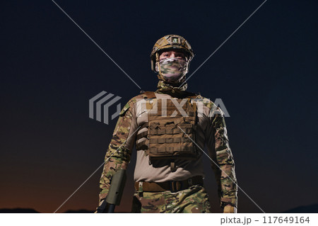 A professional soldier in full military gear striding through the dark night as he embarks on a perilous military mission 117649164