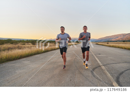 Group of handsome men running together in the early morning glow of the sunrise, embodying the essence of fitness, vitality, and the invigorating joy of embracing nature's tranquility during their Group of handsome men running together in the early morning glow of the sunrise, embodying the essence of fitness, vitality, and the invigorating joy of embracing nature's tranquility during their 117649186