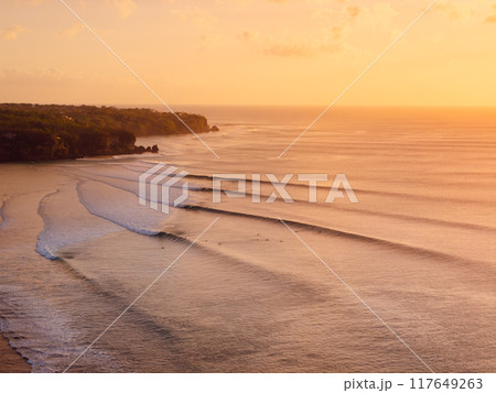 Drone view of warm sunset or sunrise and ocean with perfect long waves in Bali. 117649263