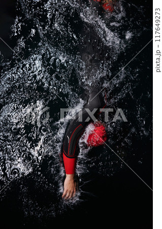 A determined professional triathlete undergoes rigorous night time training in cold waters, showcasing dedication and resilience in preparation for an upcoming triathlon swim competition A determined professional triathlete undergoes rigorous night time training in cold waters, showcasing dedication and resilience in preparation for an upcoming triathlon swim competition 117649273