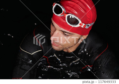 Authentic triathlete swimmer having a break during hard training on night Authentic triathlete swimmer having a break during hard training on night 117649333