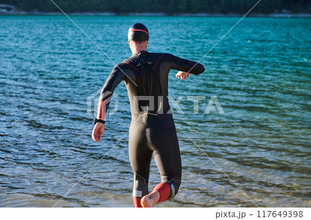 Triathlon athlete starting swimming training on lake Triathlon athlete starting swimming training on lake 117649398