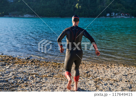 Triathlon athlete starting swimming training on lake Triathlon athlete starting swimming training on lake 117649415