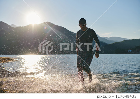 Triathlon athlete starting swimming training on lake 117649435