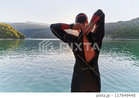 Authentic triathlon athlete getting ready for swimming training on lake Authentic triathlon athlete getting ready for swimming training on lake 117649448