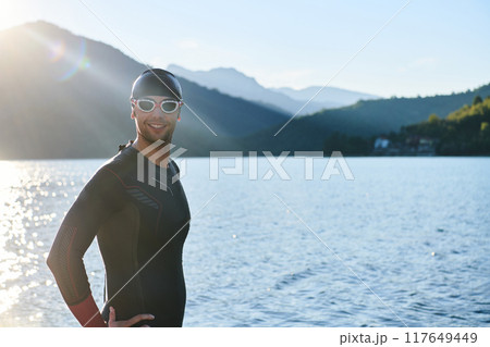 Authentic triathlon athlete getting ready for swimming training on lake 117649449