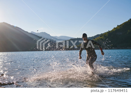 Triathlon athlete starting swimming training on lake Triathlon athlete starting swimming training on lake 117649451