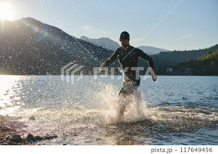 Triathlon athlete starting swimming training on lake Triathlon athlete starting swimming training on lake 117649456