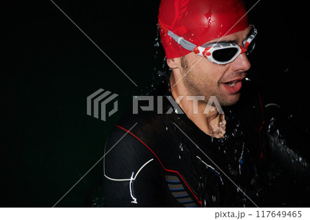 A triathlete finds serene rejuvenation in a lake, basking in the tranquility of the water after an intense training session 117649465