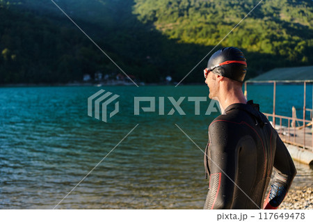 Authentic triathlon athlete getting ready for swimming training on lake 117649478