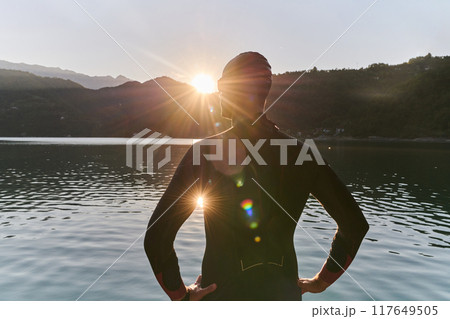 Authentic triathlon athlete getting ready for swimming training on lake Authentic triathlon athlete getting ready for swimming training on lake 117649505