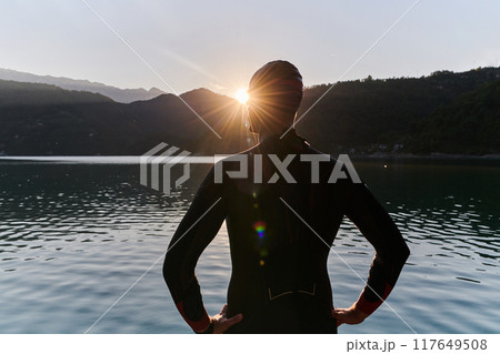 Authentic triathlon athlete getting ready for swimming training on lake Authentic triathlon athlete getting ready for swimming training on lake 117649508