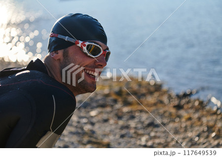Authentic triathlon athlete getting ready for swimming training on lake 117649539
