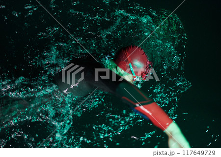A determined professional triathlete undergoes rigorous night time training in cold waters, showcasing dedication and resilience in preparation for an upcoming triathlon swim competition 117649729