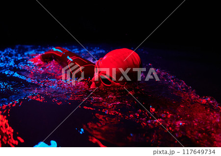 Authentic triathlete swimmer having a break during hard training on night neon gel light 117649734