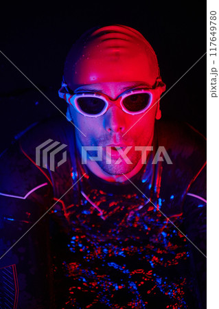 authentic triathlete swimmer having a break during hard training on night neon gel light 117649780