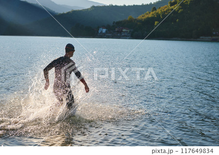 Triathlon athlete starting swimming training on lake Triathlon athlete starting swimming training on lake 117649834