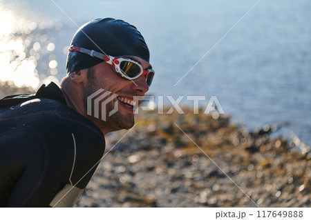 Authentic triathlon athlete getting ready for swimming training on lake Authentic triathlon athlete getting ready for swimming training on lake 117649888