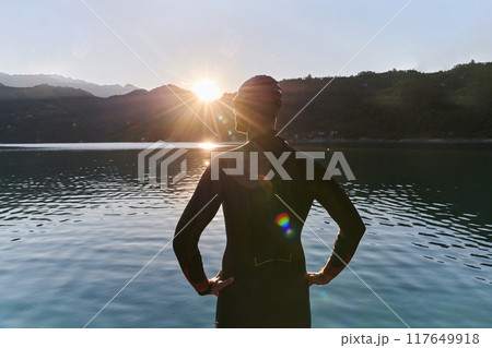 Authentic triathlon athlete getting ready for swimming training on lake Authentic triathlon athlete getting ready for swimming training on lake 117649918
