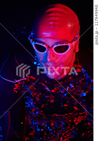 authentic triathlete swimmer having a break during hard training on night neon gel light authentic triathlete swimmer having a break during hard training on night neon gel light 117649948