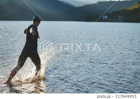 Triathlon athlete starting swimming training on lake Triathlon athlete starting swimming training on lake 117649953