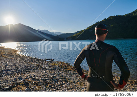 Authentic triathlon athlete getting ready for swimming training on lake Authentic triathlon athlete getting ready for swimming training on lake 117650067