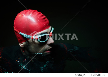 Authentic triathlete swimmer having a break during hard training on night neon gel light Authentic triathlete swimmer having a break during hard training on night neon gel light 117650107