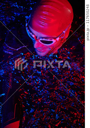 authentic triathlete swimmer having a break during hard training on night neon gel light 117650248