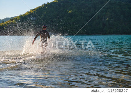 Triathlon athlete starting swimming training on lake 117650297
