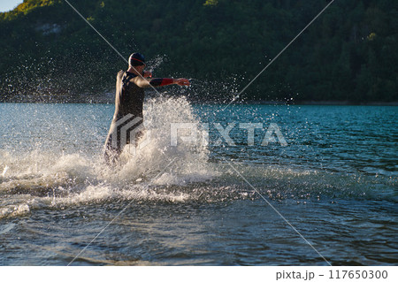 Triathlon athlete starting swimming training on lake 117650300