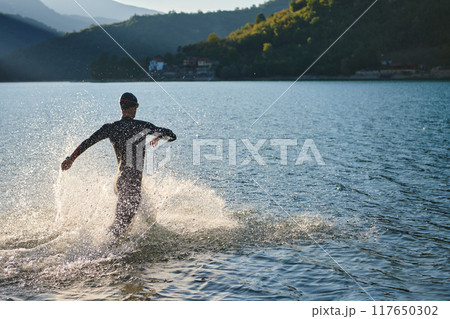 Triathlon athlete starting swimming training on lake 117650302