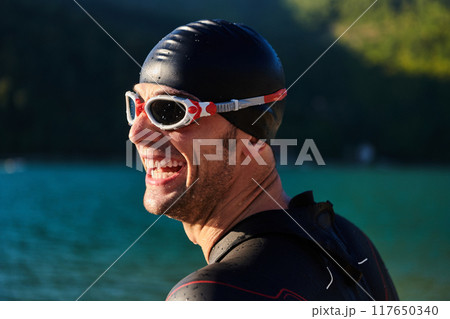 Authentic triathlon athlete getting ready for swimming training on lake Authentic triathlon athlete getting ready for swimming training on lake 117650340