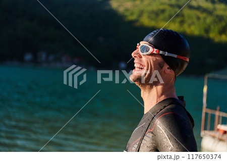 Authentic triathlon athlete getting ready for swimming training on lake 117650374