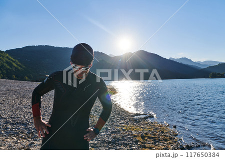 Authentic triathlon athlete getting ready for swimming training on lake Authentic triathlon athlete getting ready for swimming training on lake 117650384