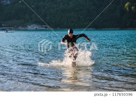 Triathlon athlete starting swimming training on lake 117650396