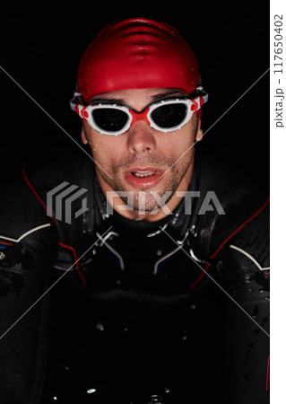 A determined professional triathlete undergoes rigorous night time training in cold waters, showcasing dedication and resilience in preparation for an upcoming triathlon swim competition 117650402