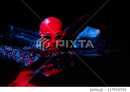 authentic triathlete swimmer having a break during hard training on night neon gel light 117650591