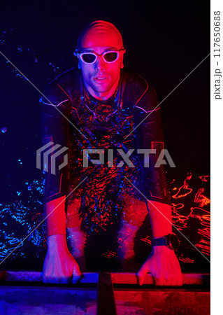 authentic triathlete swimmer having a break during hard training on night neon gel light 117650688