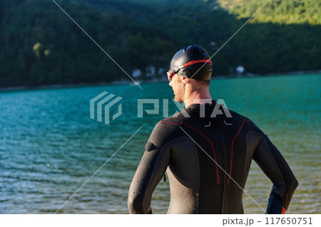Authentic triathlon athlete getting ready for swimming training on lake 117650751