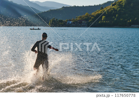 Triathlon athlete starting swimming training on lake Triathlon athlete starting swimming training on lake 117650778
