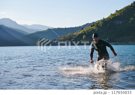 Triathlon athlete starting swimming training on lake 117650833
