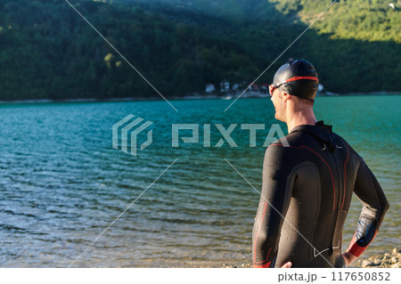Authentic triathlon athlete getting ready for swimming training on lake Authentic triathlon athlete getting ready for swimming training on lake 117650852