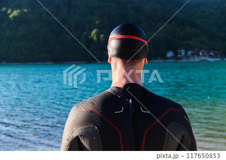 Authentic triathlon athlete getting ready for swimming training on lake 117650853