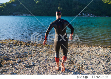 Authentic triathlon athlete getting ready for swimming training on lake 117650886