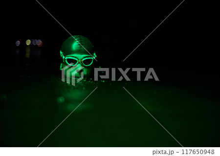 Authentic triathlete swimmer having a break during hard training on night neon gel light Authentic triathlete swimmer having a break during hard training on night neon gel light 117650948
