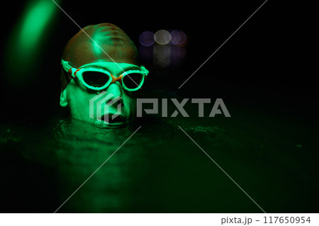Authentic triathlete swimmer having a break during hard training on night neon gel light Authentic triathlete swimmer having a break during hard training on night neon gel light 117650954