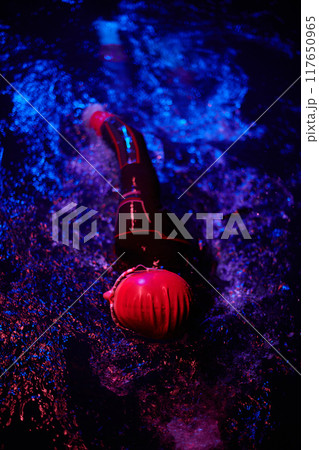 Authentic triathlete swimmer having a break during hard training on night neon gel light 117650965