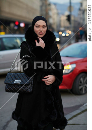 Muslim woman walking on an urban city street on a cold winter night wearing hijab Muslim woman walking on an urban city street on a cold winter night wearing hijab 117651023