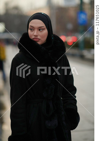 Muslim woman walking on an urban city street on a cold winter night wearing hijab Muslim woman walking on an urban city street on a cold winter night wearing hijab 117651025