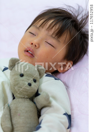 靴下ぬいぐるみを抱いて眠る2歳幼児の寝顔アップ 117652958